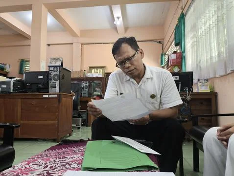 Man in glasses reads documents at an office desk Stockfoto's