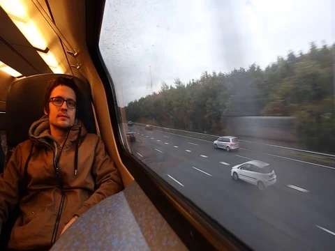 The man in glasses is riding a train along the cars road and smiling Stock Footage 83223804
