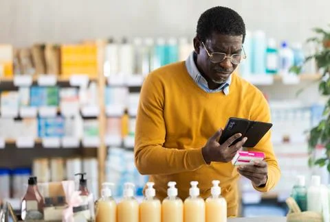 Man in glasses scans code on package of pills to check expiration date Stock-Fotos