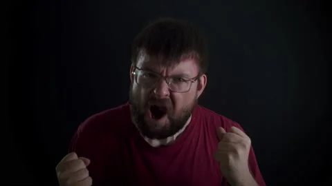 A man with glasses screams into the camera on a black background Stockbeeldmateriaal 169667744