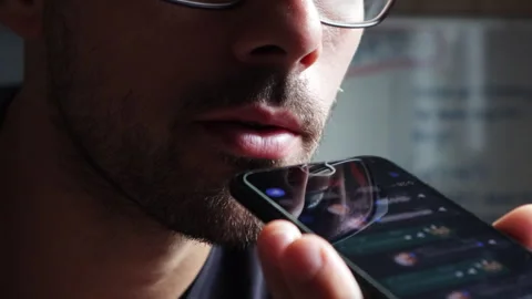 Man With Glasses Sending A Voice Message In A Dark Room Stock Footage 248764094