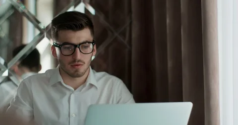 Man in glasses siting at the table, working and drink coffee or tee. Stock Footage 121796574