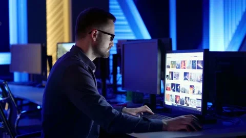 A man with glasses sits and thinks, typing on a computer in the office at night. Stock Footage 199326706