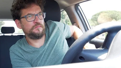 Man with glasses sitting in car putting seat belt listening music starting ca Stock Footage 79733845