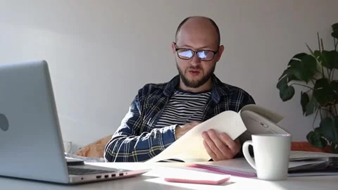 Man with glasses sorts through documents on his desk. Video stock 243372668