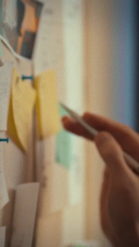 Man in glasses stands beside a wall-mounted whiteboard arranging sticky note Stock Footage 342717468