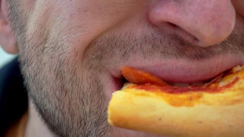 A man in glasses with stubble eats a slice of pizza in a cafe. Extrime close-up 스톡 동영상 100531437
