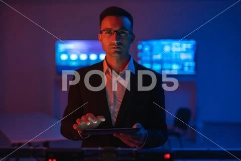 The man in glasses with a tablet working in a room with screens Stock Photos