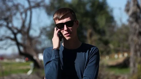 Man in glasses talking on cell phone outdoors Stock Footage 73580134