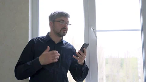 Man in glasses talking on a video call on a smartphone 4K Stock Footage 129529575
