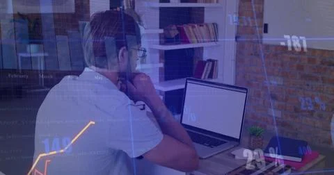 Man with glasses typing code and analyzing financial charts in home office, with Foto stock