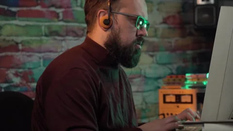 Man With Glasses Typing in Front of Desktop Monitor From 1980's While Listening Stock Footage 313576394