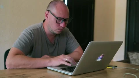 Man with glasses typing on the keyboard with focused expression. Stock Footage 243583380