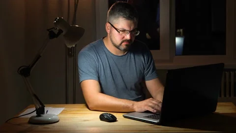 Man with glasses typing on a laptop while sitting at home 4K Stock-Footage 130150154