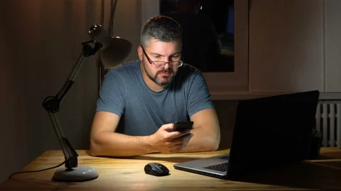 A man with glasses is viewing information on a smartphone at night 4K Stock-Footage 130150320