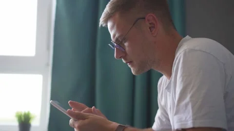A man with glasses is watching a tablet at home Stock Footage 221398685