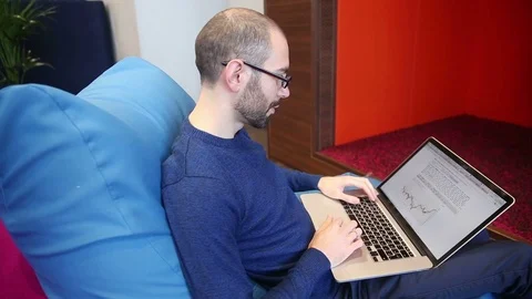 Man with glasses working on laptop Stock Footage 69977233