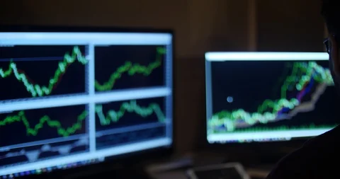 A man in glasses works with graphs on 2 monitors in dark room Stock Footage 88059089