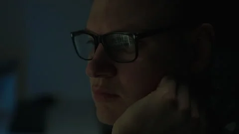 A man with glasses works at a laptop computer at night. This IT professional Stock Footage 255681466