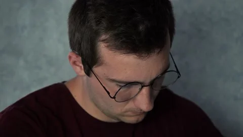 A man with glasses works at a laptop while sitting in his office Stock Footage 156228366