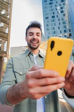 Man gleefully interacting with smartphone while enjoying a bright day outdoors 스톡 사진