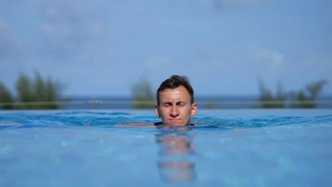 Man glides through open pool surrounded by clear skies Stock Footage 302147662