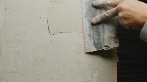 Man glides wide plastering spatula over wall smoothing out layer Stock Footage 304424585