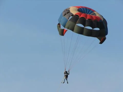 A man is gliding using a parachute on the background of cloudy blue sky Photos
