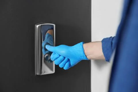 Man in glove pressing elevator call button, closeup. Protective measure Foto stock