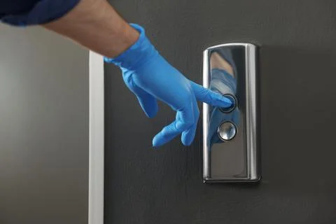 Man in glove pressing elevator call button, closeup. Protective measure Foto stock