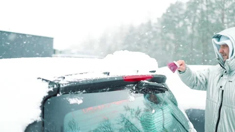 Man in gloves brushing deep snow from car windshield wiper blades Vidéo 341951363
