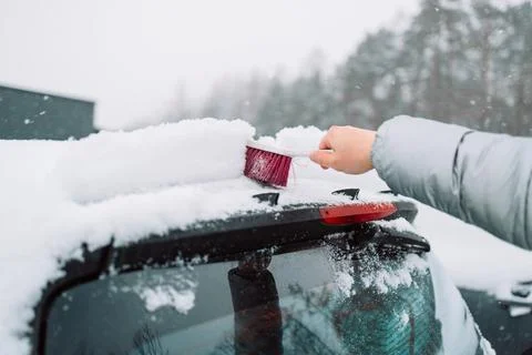 Man in gloves brushing deep snow from car windshield wiper blades Stock Photos