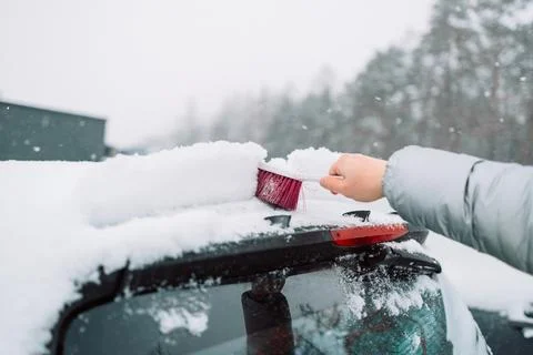 Man in gloves brushing deep snow from car windshield wiper blades Stock Photos