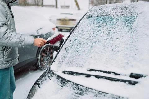 Man in gloves brushing deep snow from car windshield wiper blades Stock Photos