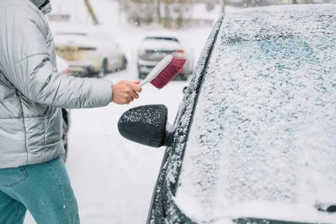 Man in gloves brushing deep snow from car windshield wiper blades Stock Photos