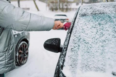 Man in gloves brushing deep snow from car windshield wiper blades Stock Photos