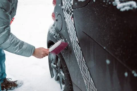 Man in gloves brushing deep snow from car windshield wiper blades Stock Photos