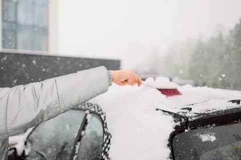 Man in gloves brushing deep snow from car windshield wiper blades Stock Photos
