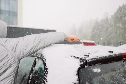 Man in gloves brushing deep snow from car windshield wiper blades Stock Photos