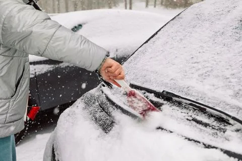 Man in gloves brushing deep snow from car windshield wiper blades Stock Photos