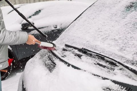 Man in gloves brushing deep snow from car windshield wiper blades Stock Photos
