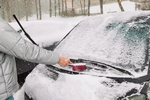 Man in gloves brushing deep snow from car windshield wiper blades Stock Photos