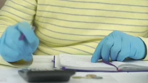Man in gloves counts on calculator and verifies data in pad Video stock 134239985
