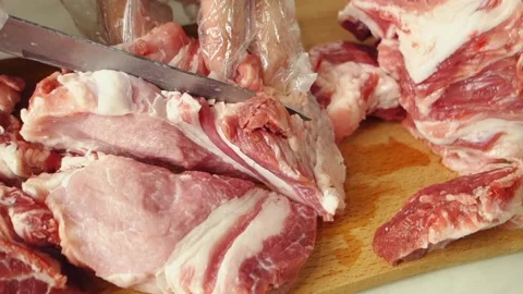 A man with gloves cuts the meat in layers. A juicy, fatty piece of meat is cut Stock Footage 144385297