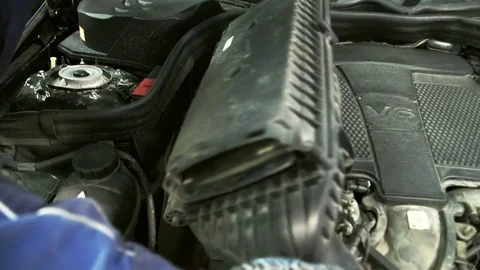 A man in gloves gently pulls out the air filter for replacement Stock Footage 75321107