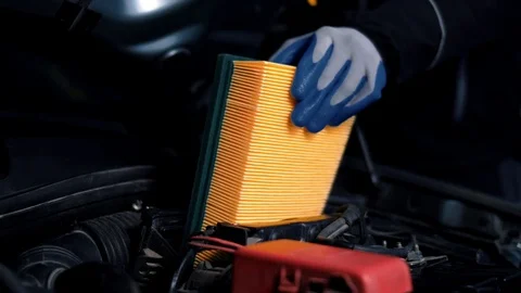 Man with gloves inserts a new air filter into a car in a service station Stock Footage 102682813