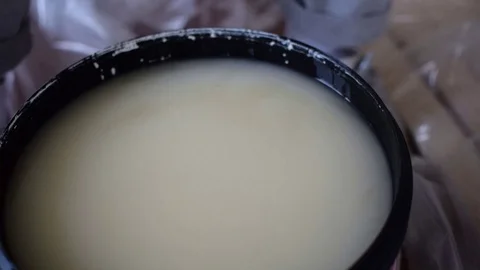 A man in gloves interferes with white paint in a container. Stock Footage 126321606