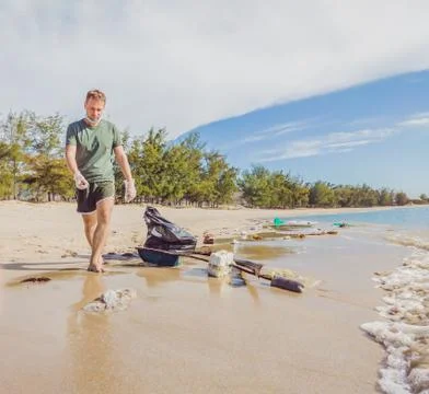 Man in gloves pick up plastic that pollute sea and forest. Problem of spilled Stock Photos