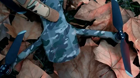Man in gloves presses the power button of the quadcopter in camouflage livery Stock Footage 139042046