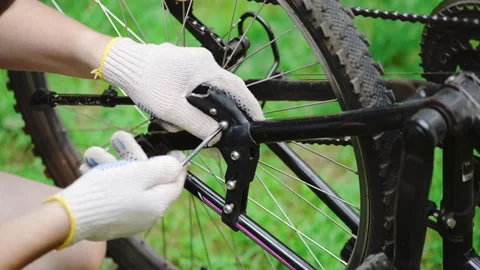 A man in gloves repairs a bicycle footstep. Maintenance of a mountain bike at Stock Footage 133914064